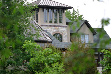 Diseño de fachada de casa beige de estilo americano de tres plantas con revestimiento de piedra y tejado de metal