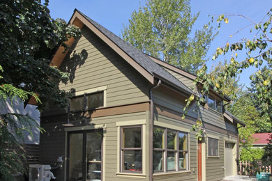 Foto de fachada de casa verde pequeña de dos plantas con revestimiento de aglomerado de cemento, tejado a dos aguas y tejado de teja de madera