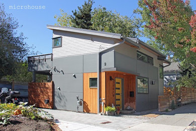 Inspiration för ett litet funkis grått hus, med två våningar, fiberplattor i betong och pulpettak