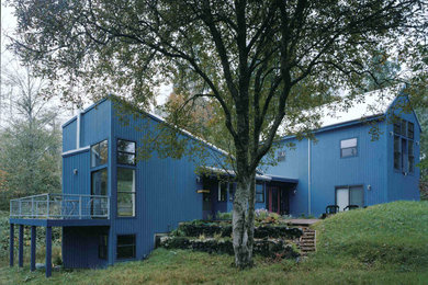 Modelo de fachada azul moderna de tamaño medio de dos plantas con revestimiento de madera y tejado de un solo tendido