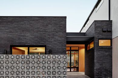 Large 1950s white two-story brick exterior home idea in Austin with a mixed material roof