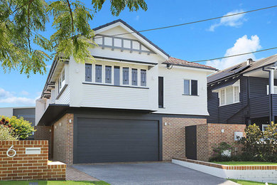 This is an example of a medium sized and white two floor detached house in Brisbane with a mixed material roof.