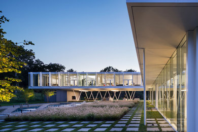 Diseño de fachada de casa blanca minimalista grande de dos plantas con revestimiento de vidrio, tejado plano y techo verde
