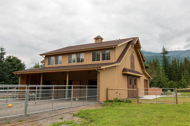 Foto della villa grande marrone country a due piani con rivestimento in legno e tetto a capanna