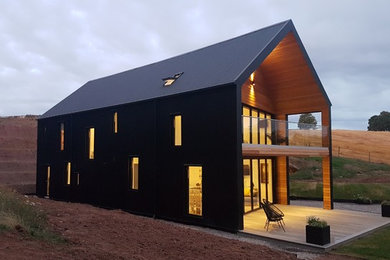 Foto de fachada de casa negra actual de tamaño medio de dos plantas con revestimiento de estuco y tejado a dos aguas