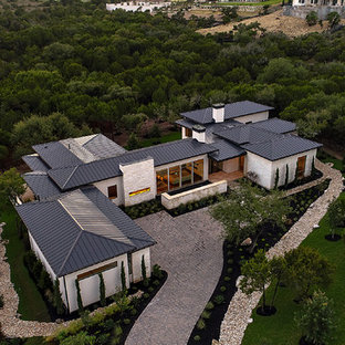 Foto de fachada de casa blanca, actual, grande, de una planta, con revestimiento de piedra y tejado de metal