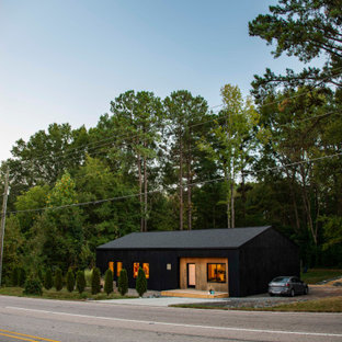 Immagine della facciata di una casa unifamiliare piccola nera scandinava a un piano con rivestimento in legno, tetto a capanna e copertura a scandole