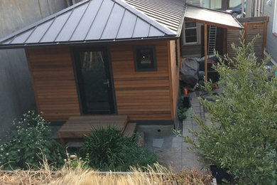 Inspiration for a small eclectic orange one-story wood house exterior remodel in Portland with a hip roof and a metal roof