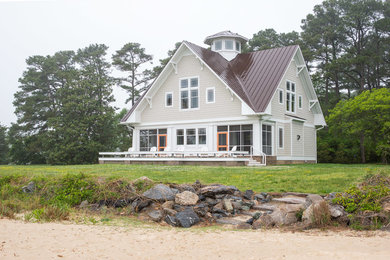 Diseño de fachada de casa beige costera grande de dos plantas con revestimiento de madera, tejado a la holandesa y tejado de metal