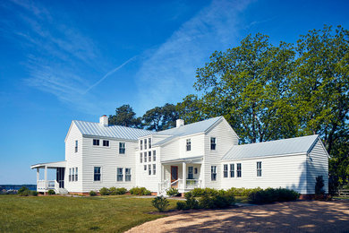 Aménagement d'une façade de maison blanche campagne à un étage avec un revêtement en vinyle et un toit en métal.
