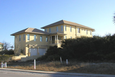 This is an example of a large and beige mediterranean concrete detached house with three floors, a hip roof and a tiled roof.