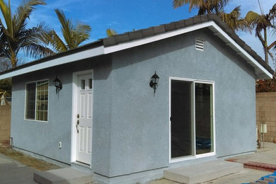 Example of a small beach style blue one-story stucco exterior home design in Orange County with a shingle roof
