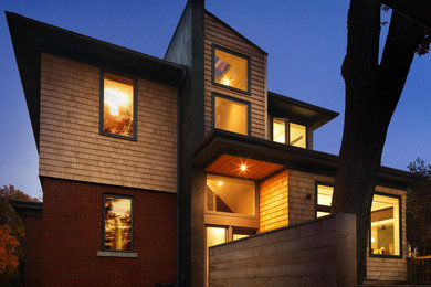 Foto de fachada moderna de dos plantas con revestimiento de madera y tejado a cuatro aguas