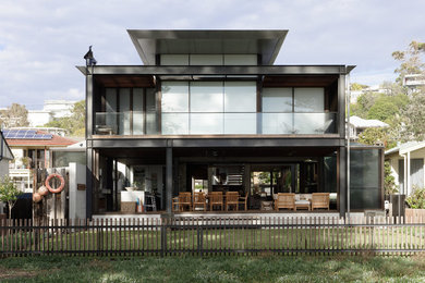 Imagen de fachada de casa gris actual de tamaño medio de dos plantas con revestimiento de hormigón, tejado plano y tejado de metal