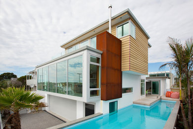 Imagen de fachada multicolor costera de tamaño medio a niveles con revestimientos combinados y tejado plano