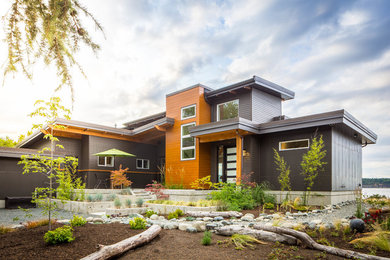 На фото: двухэтажный, серый частный загородный дом среднего размера в современном стиле с комбинированной облицовкой и односкатной крышей с
