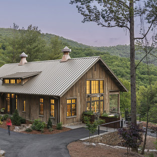 Foto de fachada de casa marrón, rural, de tamaño medio, de tres plantas, con revestimiento de madera, tejado a dos aguas y tejado de metal