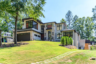 Imagen de fachada de casa gris minimalista grande de dos plantas con revestimiento de estuco, tejado a cuatro aguas y tejado de teja de madera