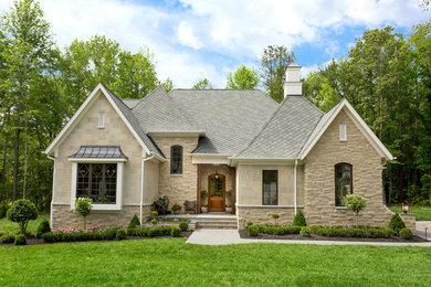 Foto della facciata di una casa beige classica a due piani di medie dimensioni con rivestimento in pietra e tetto a mansarda