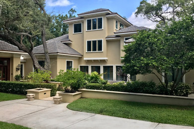 Large transitional beige three-story stucco house exterior photo in Tampa with a hip roof and a tile roof