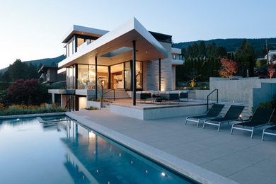 Стильный дизайн: большой, трехэтажный, бежевый частный загородный дом в современном стиле с облицовкой из камня и плоской крышей - последний тренд