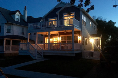 Aménagement d'une grande façade de maison bleue bord de mer à un étage avec un revêtement en vinyle, un toit à deux pans et un toit en shingle.