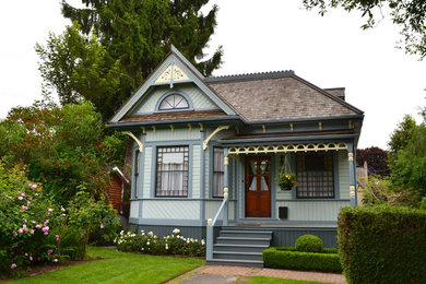 Modelo de fachada de casa azul tradicional de tamaño medio de dos plantas con revestimiento de madera