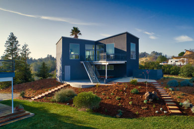 Ejemplo de fachada de casa azul moderna grande de dos plantas con revestimientos combinados, tejado plano y tejado de varios materiales