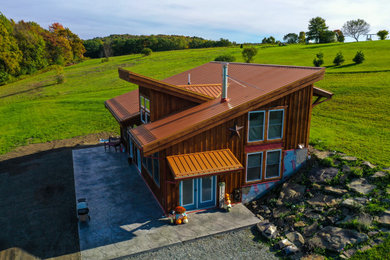 Diseño de fachada de casa marrón rural de tamaño medio de dos plantas con revestimiento de madera, tejado de un solo tendido y tejado de metal
