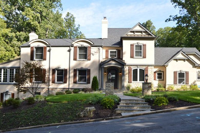 Foto della facciata di una casa beige classica a due piani con rivestimento in stucco e tetto a capanna