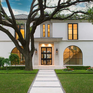 Foto de fachada de casa blanca, actual, grande, de dos plantas, con revestimiento de estuco, tejado a cuatro aguas y tejado de teja de barro