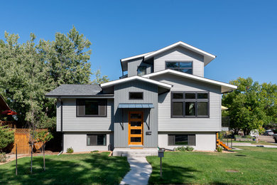 Imagen de fachada de casa gris actual con revestimientos combinados, tejado a dos aguas y tejado de teja de madera