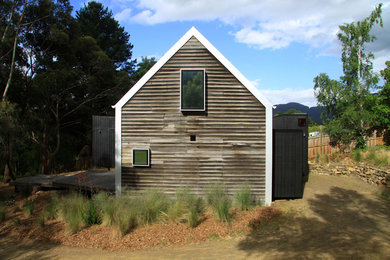 Ejemplo de fachada de casa marrón campestre pequeña de dos plantas con revestimiento de madera, tejado de un solo tendido y tejado de metal