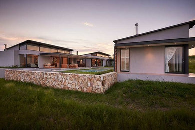 Пример оригинального дизайна: большой, одноэтажный, серый частный загородный дом в современном стиле с облицовкой из цементной штукатурки