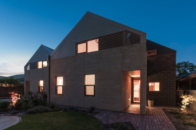 Aménagement d'une façade de maison moderne en panneau de béton fibré de taille moyenne et à un étage avec un toit à deux pans.