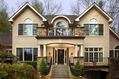 Large traditional beige two-story house exterior idea in Other with a clipped gable roof and a shingle roof