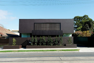 Immagine della facciata di una casa grande nera moderna a due piani con rivestimento in cemento e tetto piano