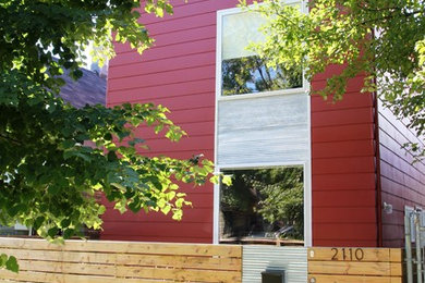 This is an example of a medium sized and red contemporary two floor house exterior in Chicago with wood cladding and a pitched roof.
