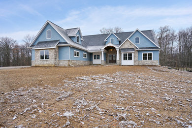 Diseño de fachada de casa azul tradicional grande de dos plantas con revestimientos combinados, tejado a dos aguas y tejado de teja de madera