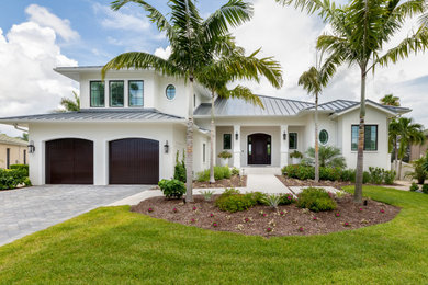 Inspiration for a tropical white two-story house exterior remodel in Tampa with a hip roof and a metal roof