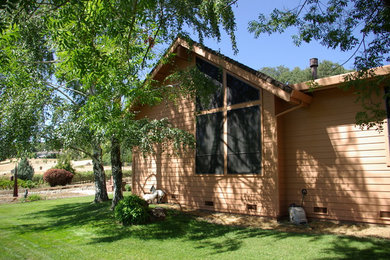 Ejemplo de fachada de casa beige clásica de tamaño medio de una planta con revestimiento de madera, tejado a dos aguas y tejado de teja de madera