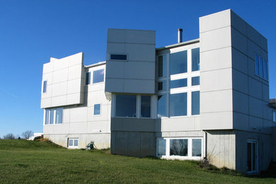 Aménagement d'une façade de maison beige moderne en panneau de béton fibré de taille moyenne et à un étage avec un toit à deux pans.