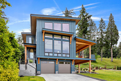 Modelo de fachada de casa azul costera grande de tres plantas con revestimiento de aglomerado de cemento, tejado de un solo tendido y tejado de metal