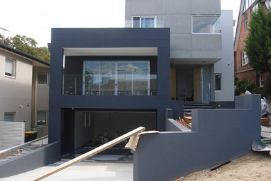 Cette image montre une grande façade de maison bleue design en béton à deux étages et plus avec un toit plat et un toit mixte.