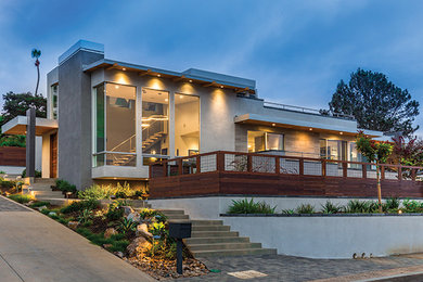 Cette photo montre une façade de maison grise moderne en stuc de taille moyenne et de plain-pied avec un toit plat.