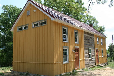 Cette image montre une façade de maison jaune chalet à un étage et de taille moyenne avec un revêtement mixte, un toit à deux pans et un toit en métal.