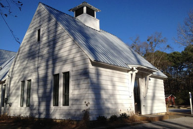Ejemplo de fachada de casa blanca de estilo de casa de campo de tamaño medio de una planta con revestimiento de madera, tejado a dos aguas y tejado de metal