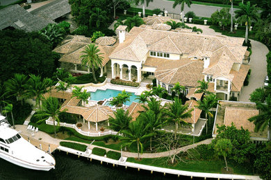 Imagen de fachada de casa blanca mediterránea extra grande de dos plantas con revestimiento de estuco, tejado a cuatro aguas y tejado de teja de barro