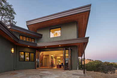 Diseño de fachada de casa verde actual de tamaño medio de dos plantas con revestimiento de estuco, tejado plano y tejado de varios materiales