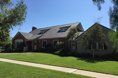 Large trendy gray two-story brick gable roof photo in Los Angeles